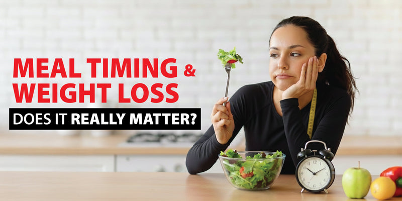Woman sitting with a bowl of salad and a clock on the table representing meal timing and its effect on weight loss.