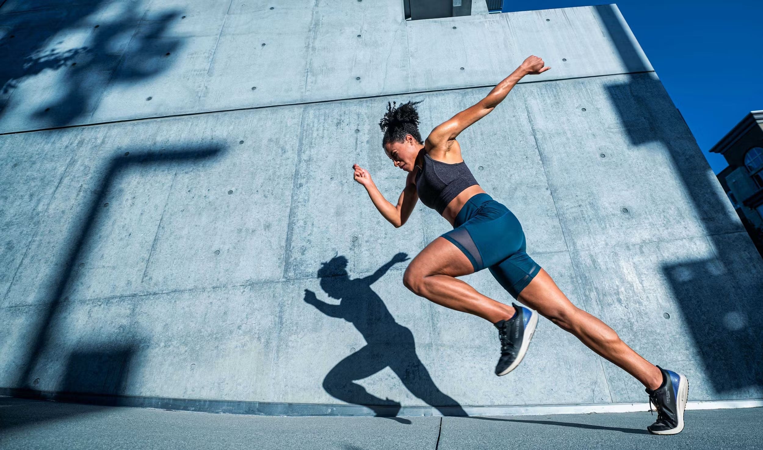 A woman jogging in front of a wall.
